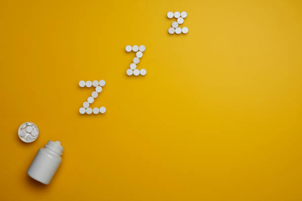 istock White round somnifacient pills on yellow background. 1130972525
