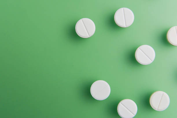 istock Pills, medicals, drugs, tablets in white, unpacked on green background with deep shadows. Flat lay. 1130972848