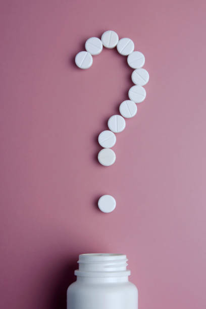istock Question mark made of white pills on pink background. Symbol question mark from whited tablets on pink background. What medicines to choose better, what will help 1130972903