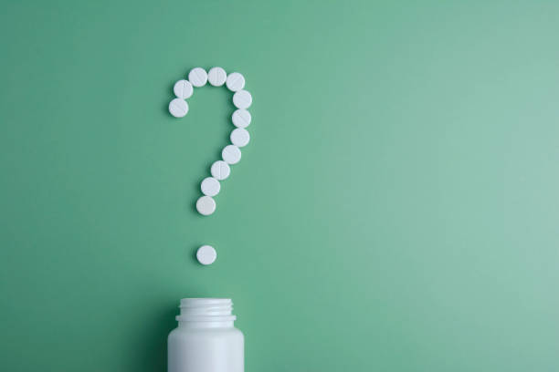 istock health problem concept with white pills arrange to question mark Question mark made of white pills on green background. What medicines to choose better, what will help. Copy space. 1130972906