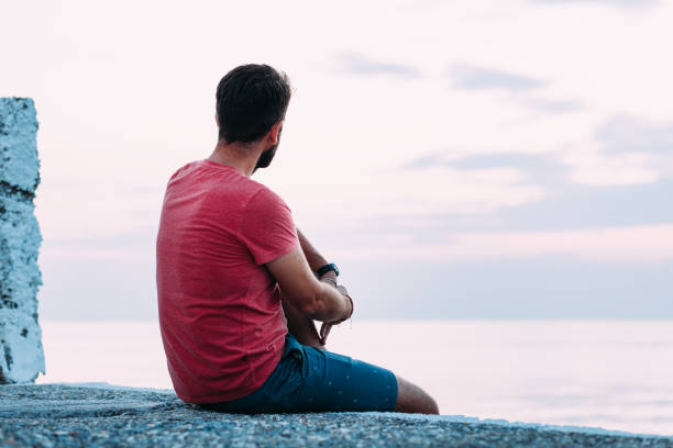 istock Young man enjoying blue hour by the sea 1130973010