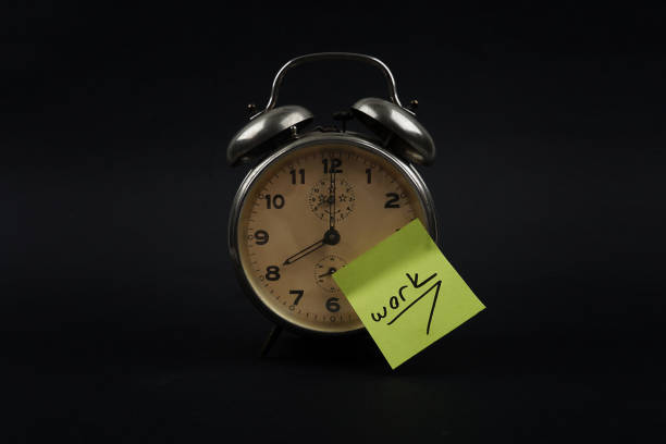 istock Alarm Clock And A yellow Post It Not Over Black Background 1130973217