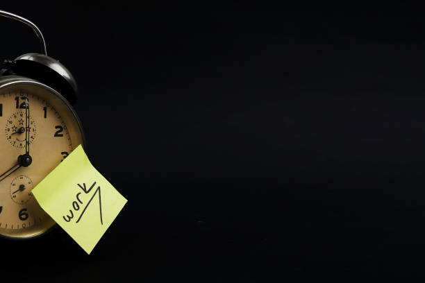 istock Alarm Clock And A yellow Post It Not Over Black Background 1130974409