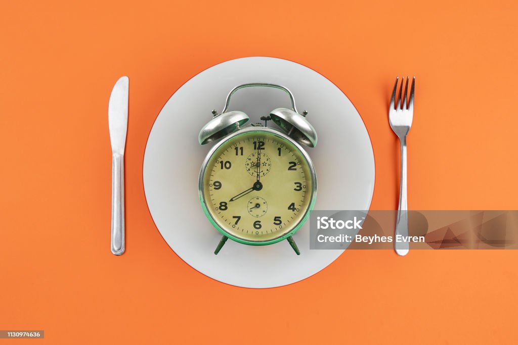 Time to eat with clock plate fork Fasting - Activity Stock Photo
