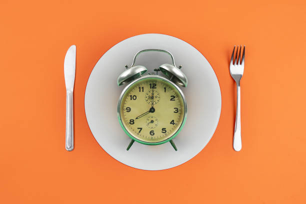 Time to eat with clock plate fork stock photo