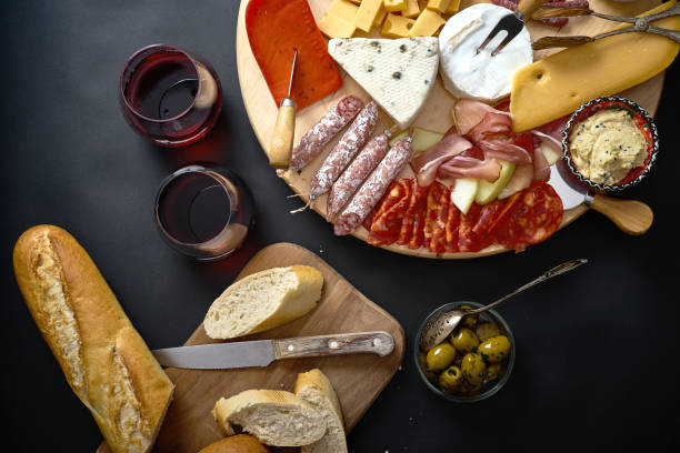 istock Antipasti board with cheese and meat snacks with red wine and baguette on board on black table 1130981205