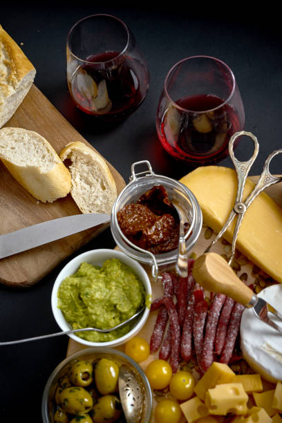 istock Antipasti board with cheese and meat snacks with red wine and baguette on board on black table 1130981336