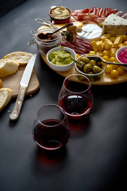 istock Antipasti board with cheese and meat snacks with red wine and baguette on board on black table 1130981362