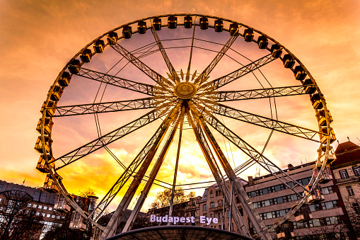 This pic shows Budapest eye Ferris wheel at sunset in budapest city. The Ferris wheel is illuminated at sunset evening. The pic is taken in jauary 2019.