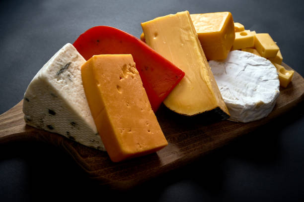 istock Wooden board with different kinds of cheeses on black table 1130981500
