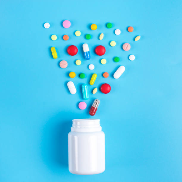 istock Assorted pharmaceutical medicine pills, tablets and white bottle on blue background. Copy space for text 1130981864