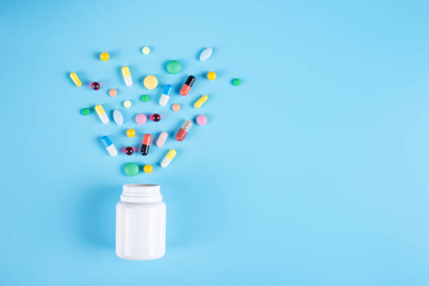 Assorted pharmaceutical medicine pills, tablets and white bottle on blue background. Copy space for text