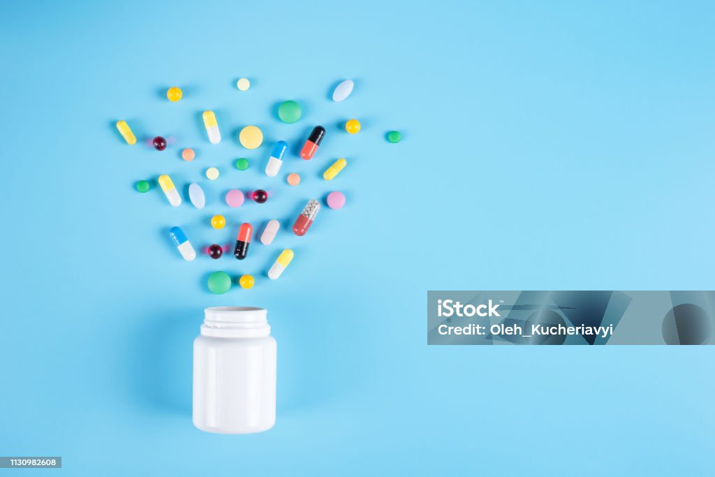 Comprimidos assorted da medicina farmacêutica, tabuletas e frasco branco no fundo azul. Copie o espaço para o texto - Foto de stock de Remédio royalty-free
