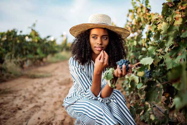 istock Young black woman eating a grape in a vineyard 1130982784