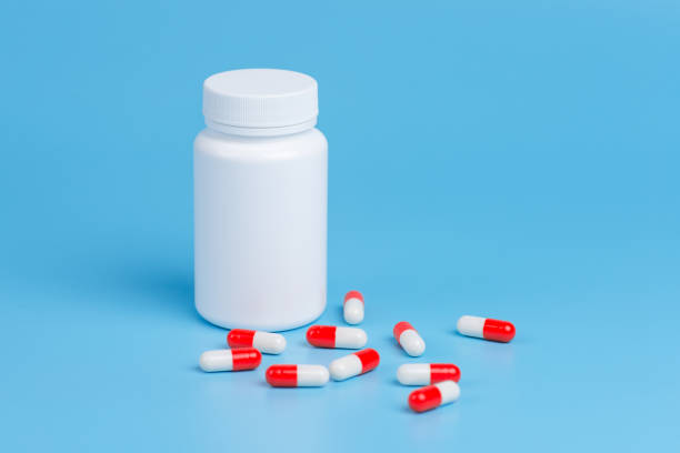 istock White and red pills, tablets and white bottle on blue background.  Copy space for text 1130982995