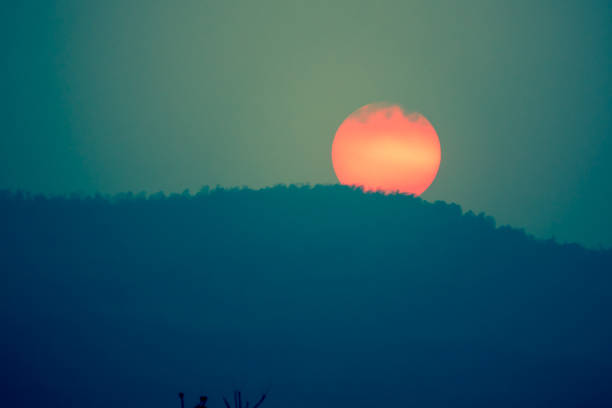 Big red sunset on hills on dark background