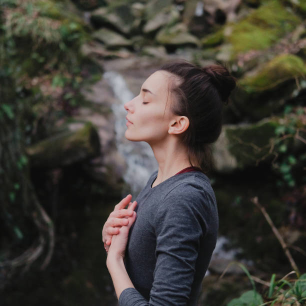 jeune femme pratiquant la respiration yoga pranayama à l'extérieur dans la forêt de mousse sur le fond de la cascade. l'unité avec le concept de la nature. - moss side photos et images de collection