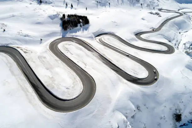 Aerial view of mountain pass, curvy, winding Alpine road with cars in winter, Julier Pass, Canton of Graubunden, Switzerland.