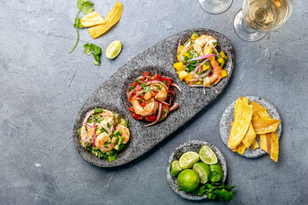 CEVICHE. Three colorful shrimps ceviche with mango, avocado and tomatoes. Latin American Mexican Peruvian Ecuadorian food. Served with white wine and banana chips stock photo