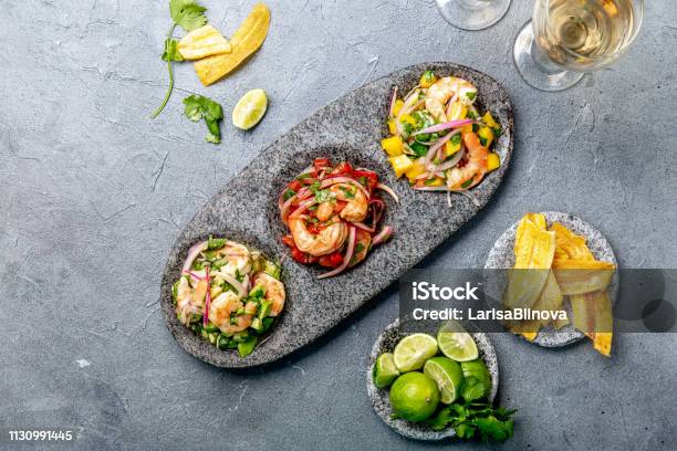 Ceviche Three Colorful Shrimps Ceviche With Mango Avocado And Tomatoes Latin American Mexican Peruvian Ecuadorian Food Served With White Wine And Banana Chips Stock Photo - Download Image Now