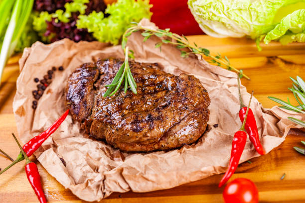 istock Grilled meat with spices and herbs  on wooden board 1130991916