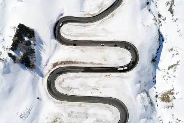 Aerial view of curvy, winding Alpine road with traffic in winter, Julier Pass, Canton of Graubunden, Switzerland.