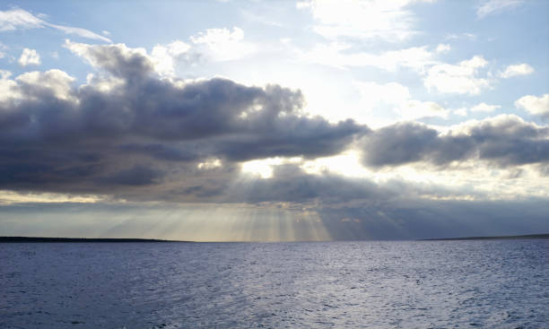 istock Sun behind cloudy and stormy sky above blue sea surface. Blue nature background 1130997632