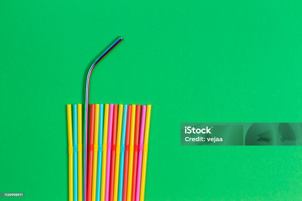 Stainless steel reusable drinking straw with plastic straws on green background Stainless steel reusable drinking straw with plastic straws on green background. Zero Waste Stock Photo