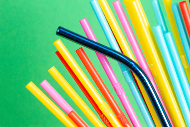 istock Stainless steel reusable drinking straw with plastic straws on green background 1130998989