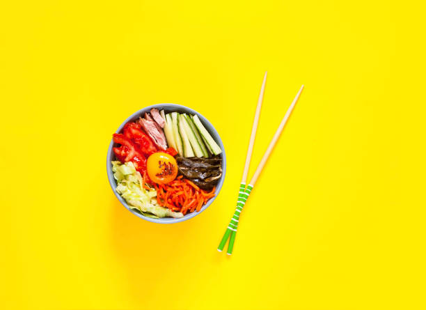 Traditional dish of Korean cuisine. Bibimbap with beef, vegetables and egg on yellow background.