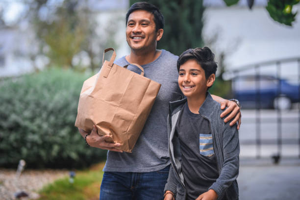 Man carrying grocery bag by son in yard