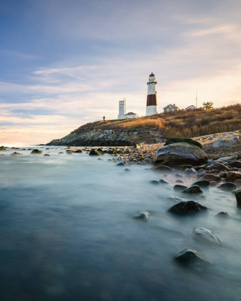 farol que senta-se em um penhasco que negligencia o oceano durante o por do sol. parque estadual de montauk, nova iorque - montauk lighthouse - fotografias e filmes do acervo