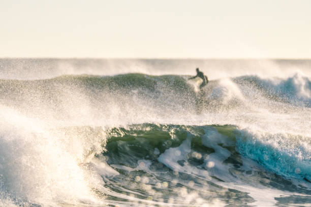 Large waves with a surfer in the background. Abstract background - Long Island New York montauk point stock pictures, royalty-free photos & images