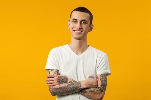 Studio portrait of a 20 year old man in a white T-shirt on a yellow background