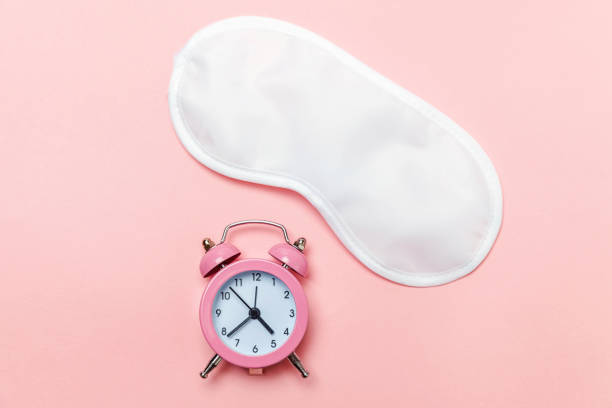 istock Sleeping mask and alarm clock on pink pastel background 1131026622