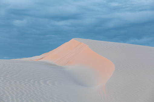 Beautiful white sand dune under cloudy sunset skies. Anna Bay, New South Wales, Australia