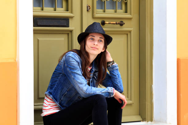Happy friendly young woman leaving the room reaching for the door as she looks back with a beaming smile