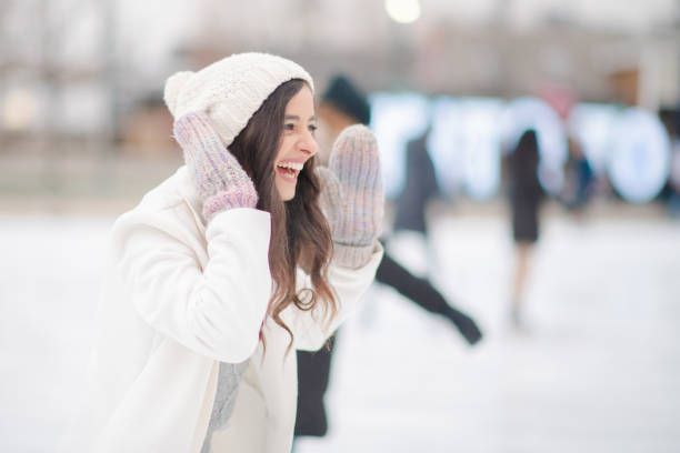A smiling woman with a red scarf enjoys a snowy winter day in a serene forest setting beneath a bright blue sky. Christmas and New Year celebration concept.