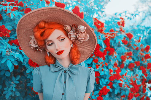 Valentines Day background. Vintage girl with red lips in awesome mint dress. Summer flowers aroma. Woman portrait. Awesome redhead model on background of roses bush. Summer trend in vintage style