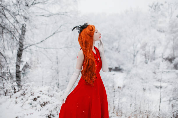 schöne schneemädchen mädchen mit roten haaren auf winter-natur. schöne rotschopf retro-frau in rotem kleid und mit langen handschuhen auf dem hintergrund der winternatur. schneefall im winter. weiße retro-handschuhe - mount misen stock-fotos und bilder