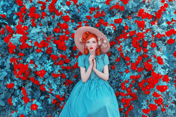 fond de jour de valentines. jardin de fleur de rose de printemps. dame fabuleuse avec des lèvres rouges dans la robe. jardinage à la ferme. mur de fleurs impressionnant. dame rousse sur le fond fabuleux de la roseraie. jardinage de printemps - fashion glamour women retro revival photos et images de collection