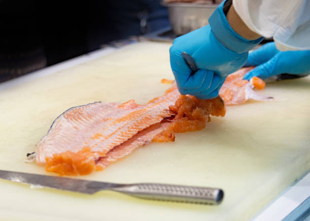 istock chef slicing raw fresh salmon, Chef preparing a fresh salmon on a cutting board 1131046444