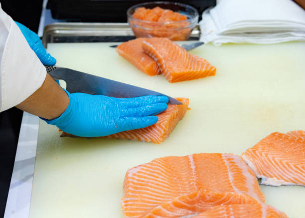 istock chef slicing raw fresh salmon, Chef preparing a fresh salmon on a cutting board 1131046487