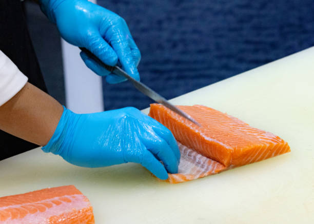 istock chef slicing raw fresh salmon, Chef preparing a fresh salmon on a cutting board 1131046499