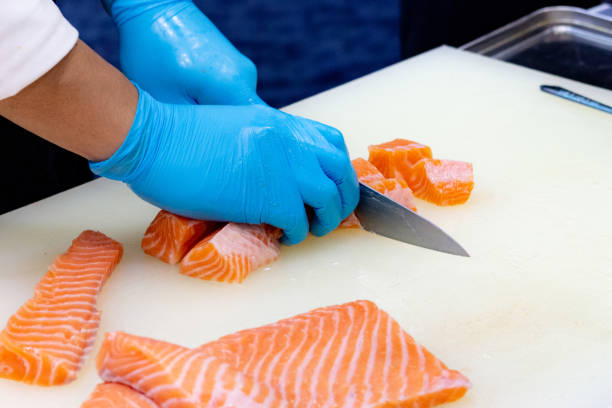 istock chef slicing raw fresh salmon, Chef preparing a fresh salmon on a cutting board 1131046507
