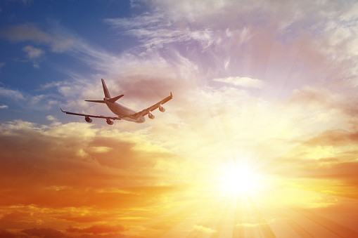 Airplane flying under sunset.