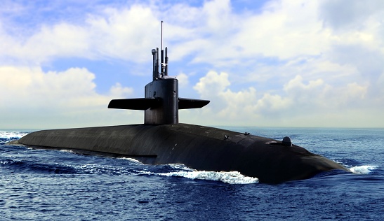 Naval submarine on open blue sea surface under cloudy sky