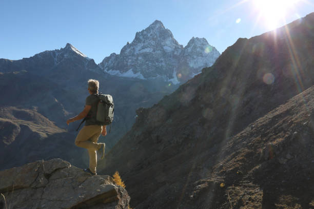 istock Hiker explores mountains in sunlight below snowcapped peak 1131057442