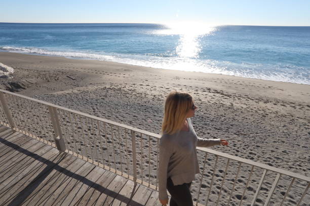 istock Young woman walks down boardwalk along the sea 1131063342