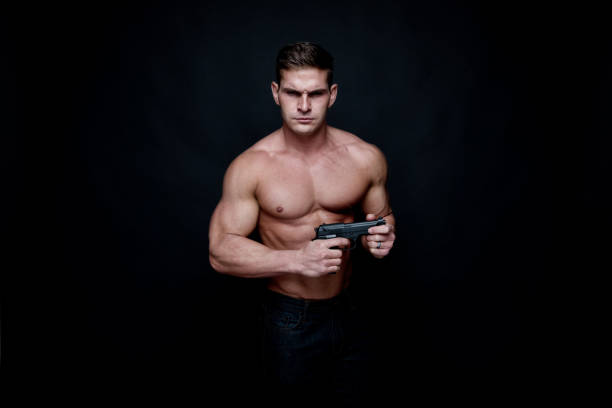 istock Shirtless muscular man holding a handgun 1131066788